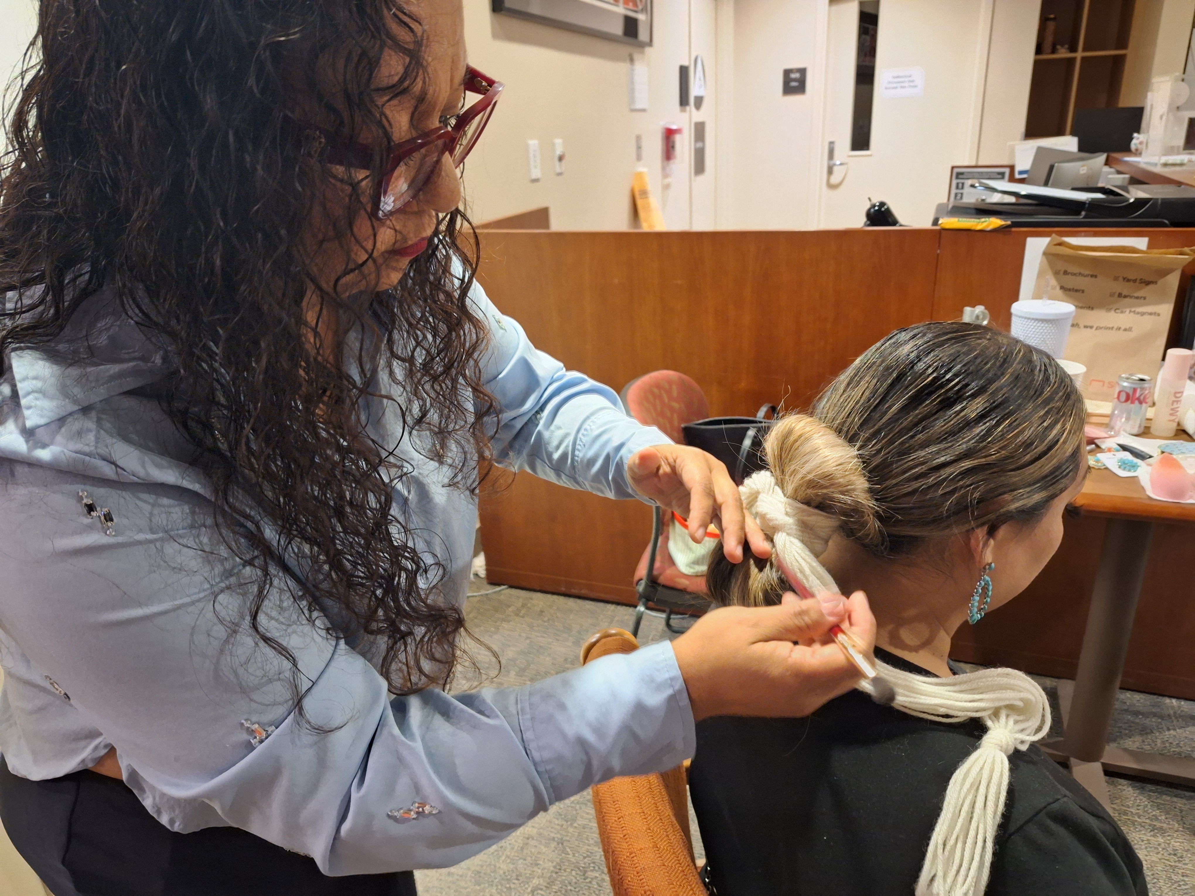 A woman helps wrap the hair of another woman for her photo session. 