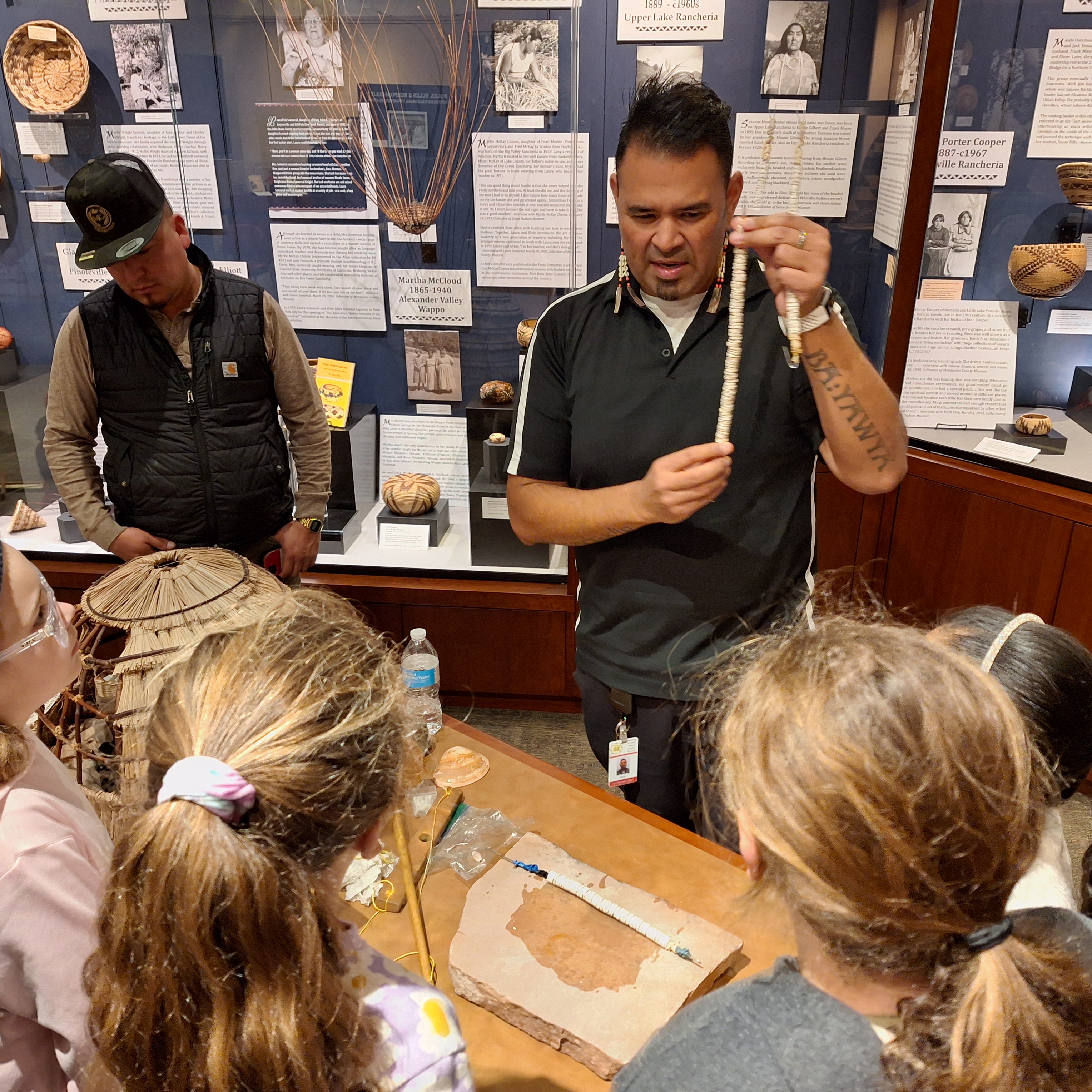 A man showing children a string of clamshell beads